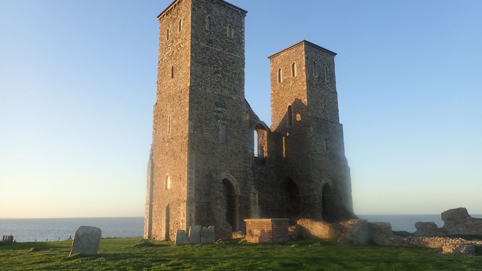 The twin towers of Reculver standing on a grassy headland above the sea