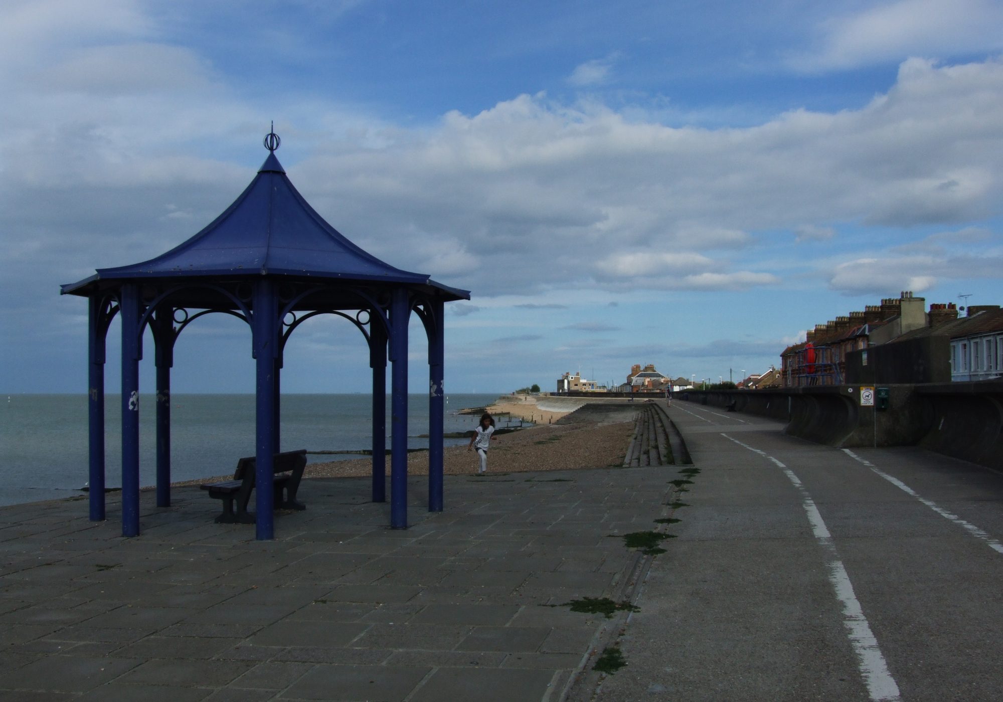 The blue seafront shelter and promenade at Sheerness, with the shingle beach and the Thames Estuary beyond